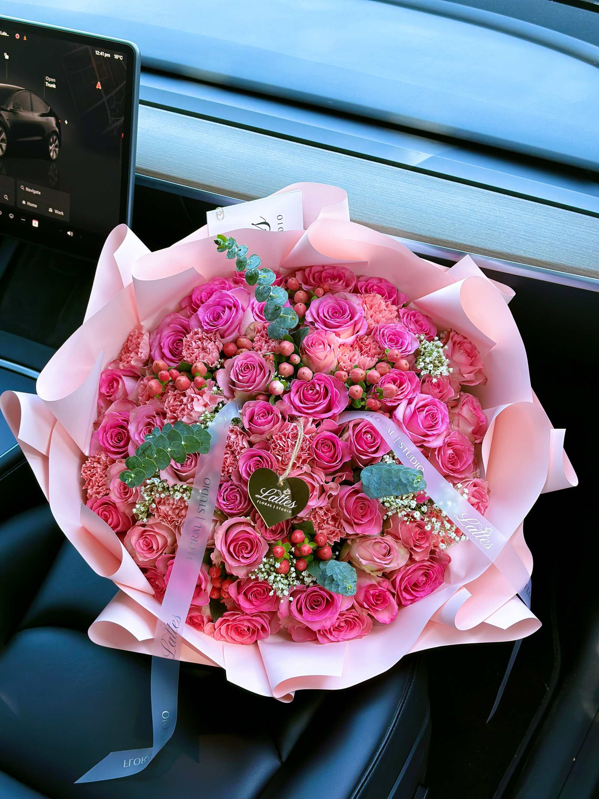 Pink Symphony bouquet with pink roses, carnations, hypericum berries, baby's breath, and eucalyptus in pink wrapping