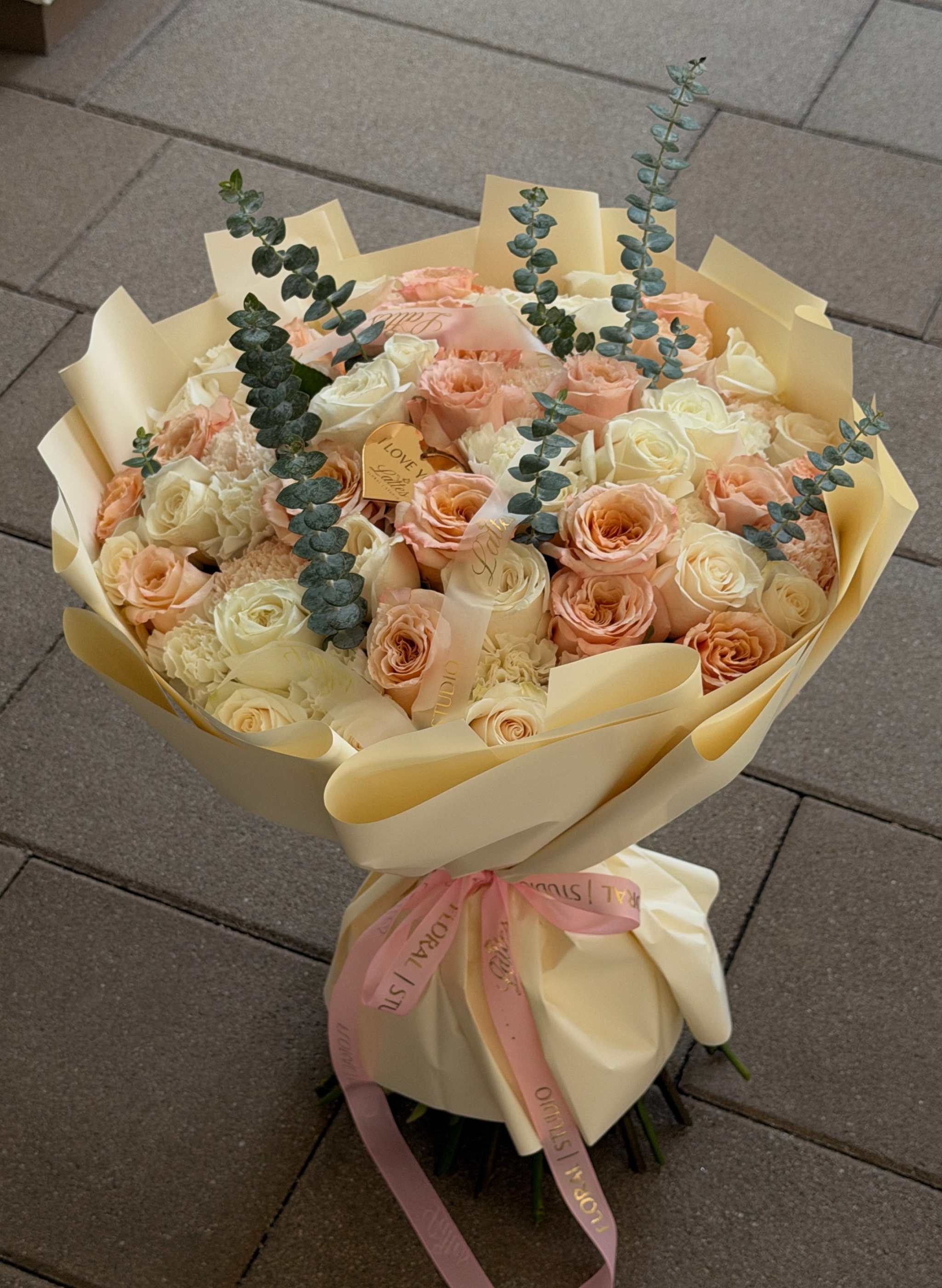 Peach Cloud bouquet with peach and white roses, cream hydrangea, and eucalyptus in tall hand-tied arrangement