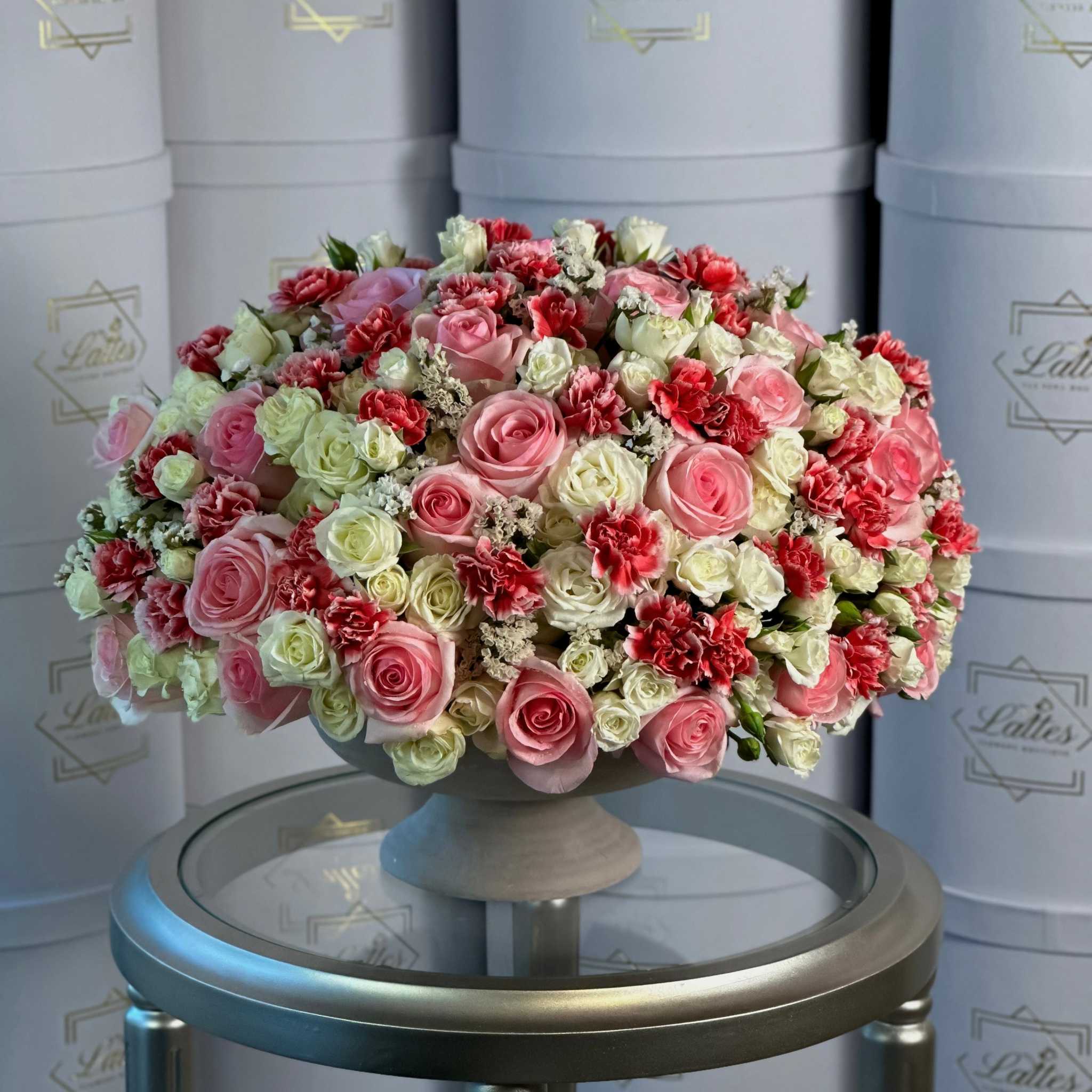 Eterna floral arrangement with pink and white roses and vibrant carnations in a classic pedestal vase