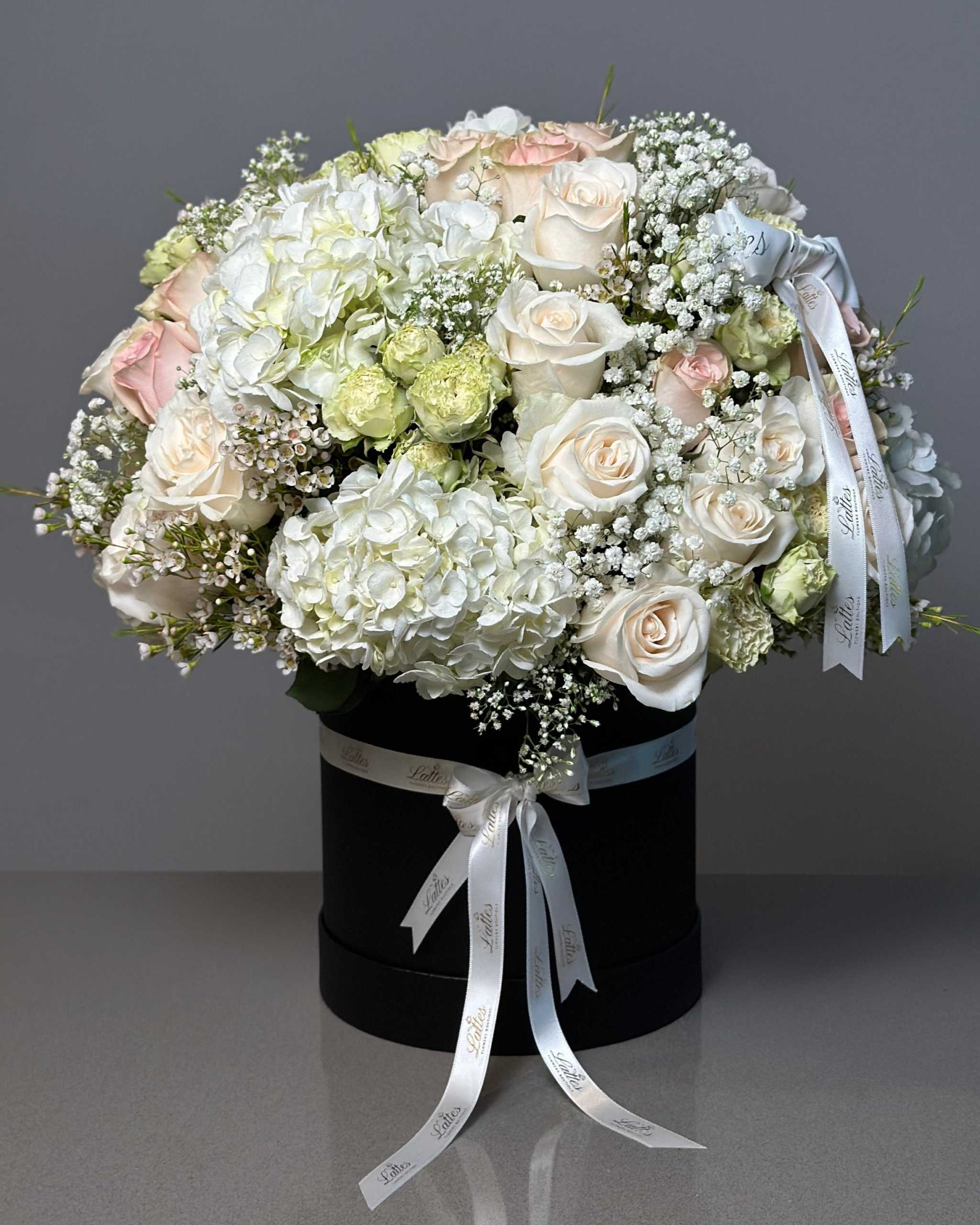Luxurious flower box with white and blush roses, hydrangeas, and baby's breath in a black box