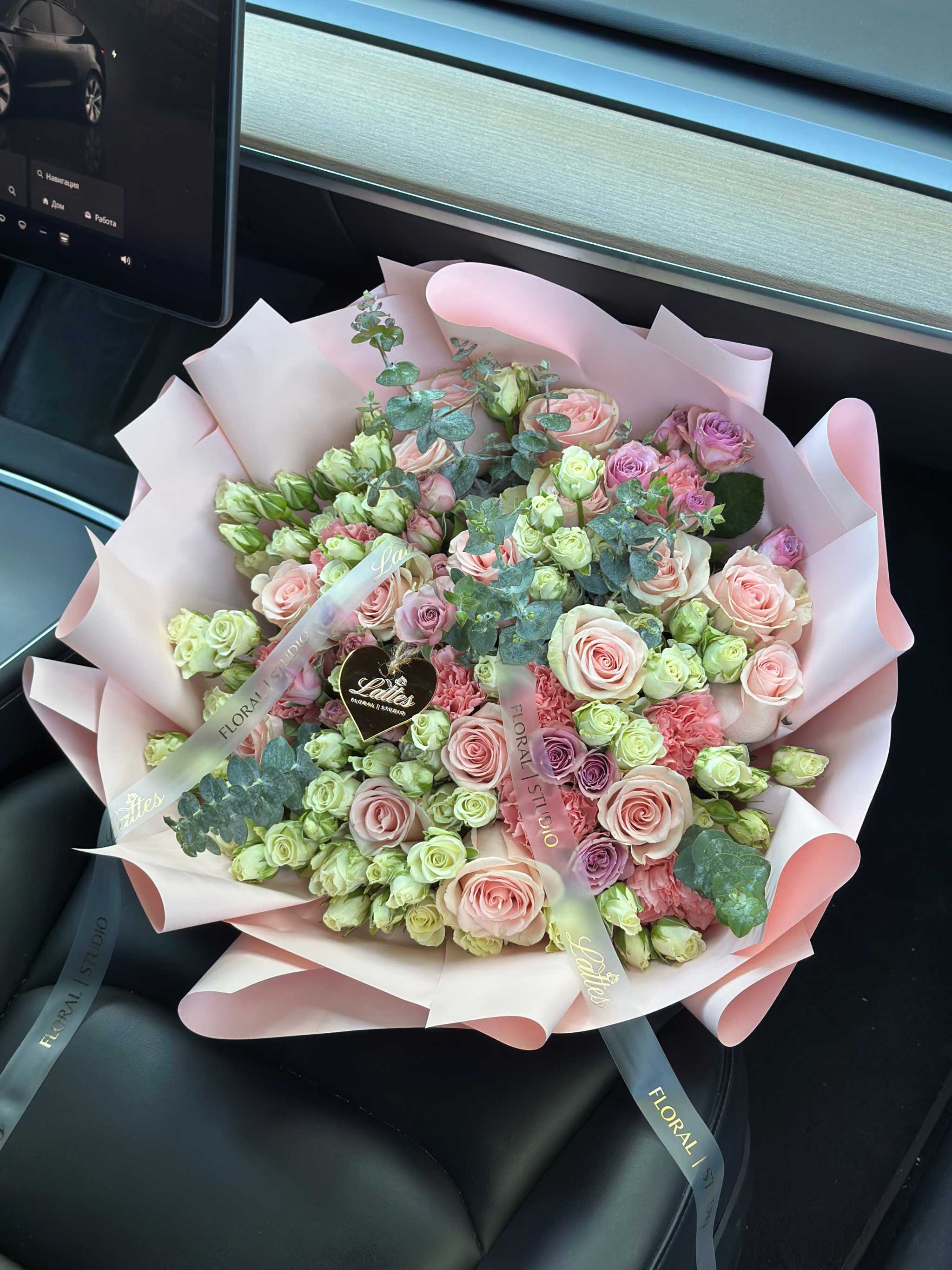 Pink and white spray roses bouquet with eucalyptus and pastel carnations in pale pink wrapping