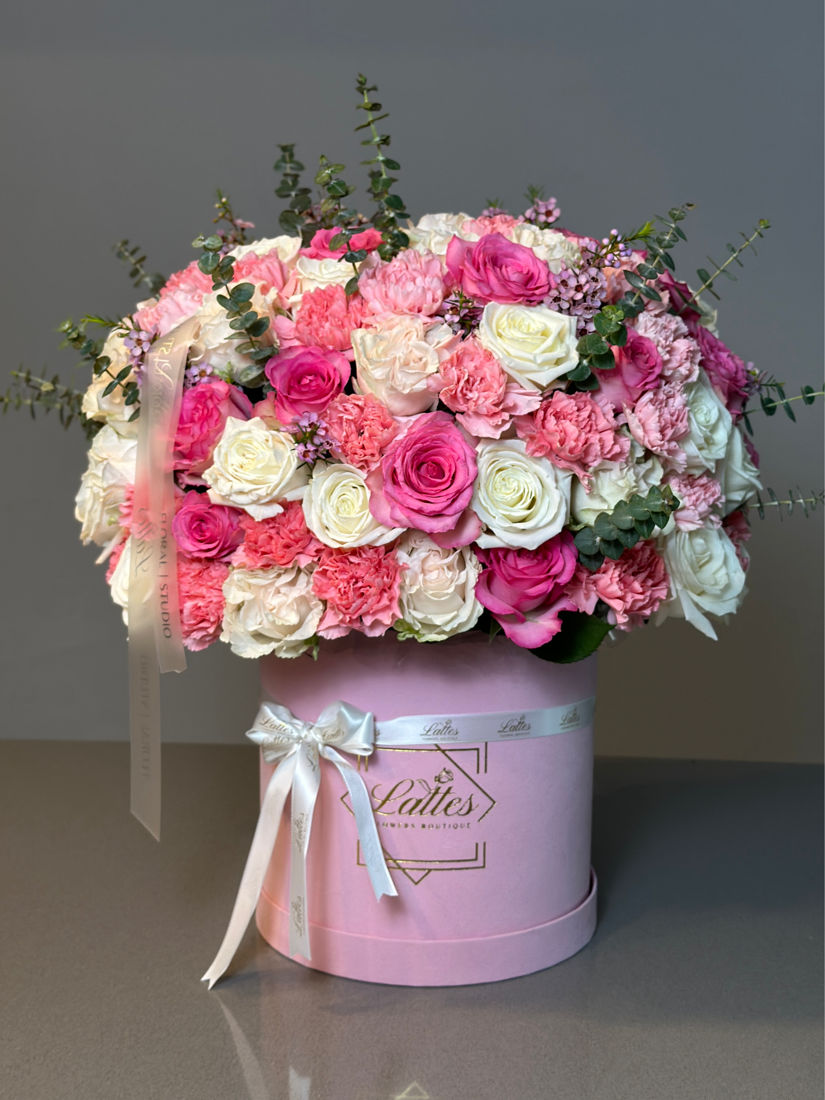Luxury pink and white flower box with roses, carnations, and eucalyptus in a pink hatbox