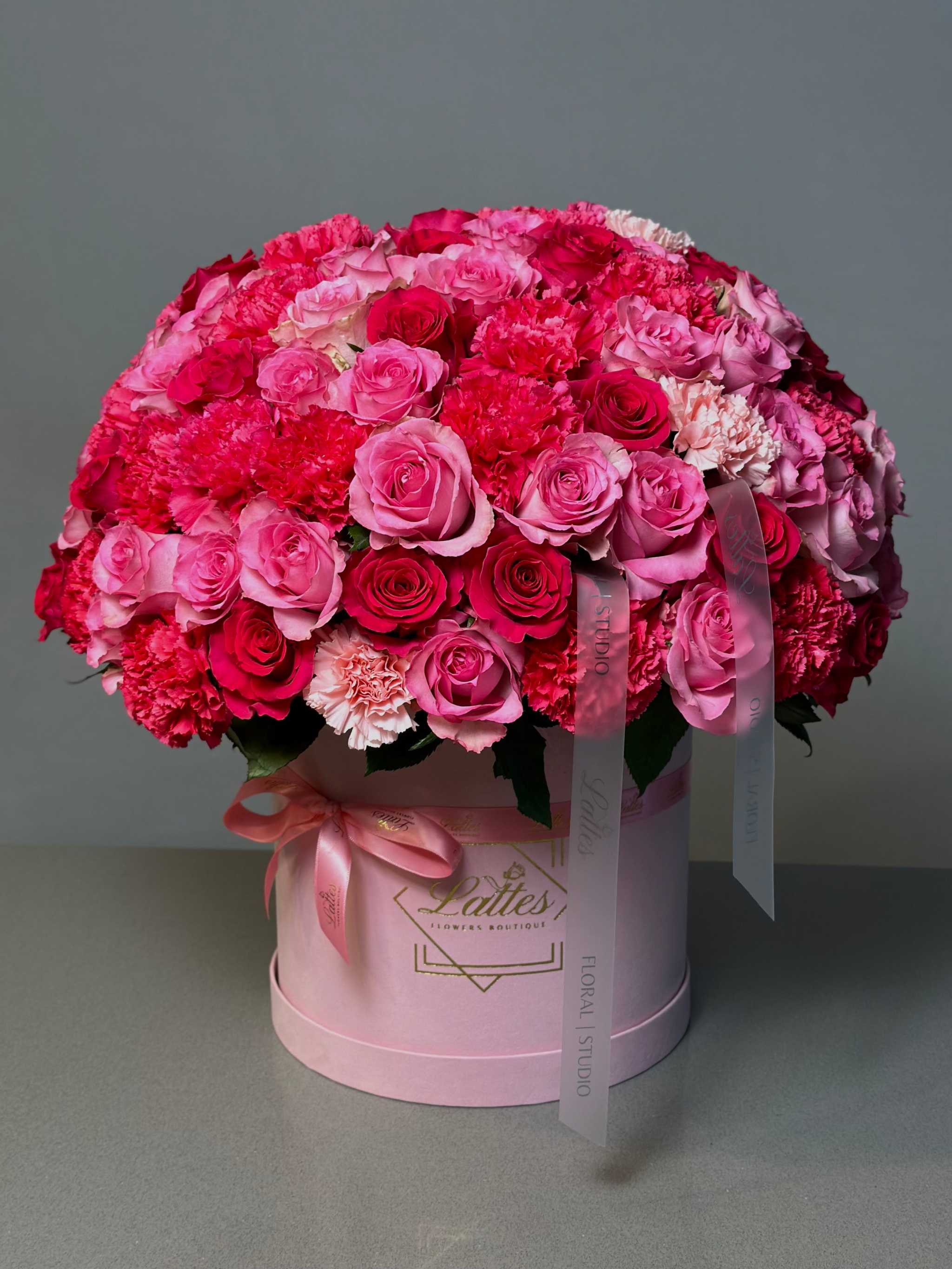 Blushing Charm pink roses and carnations arranged in a pink flower box with ribbons