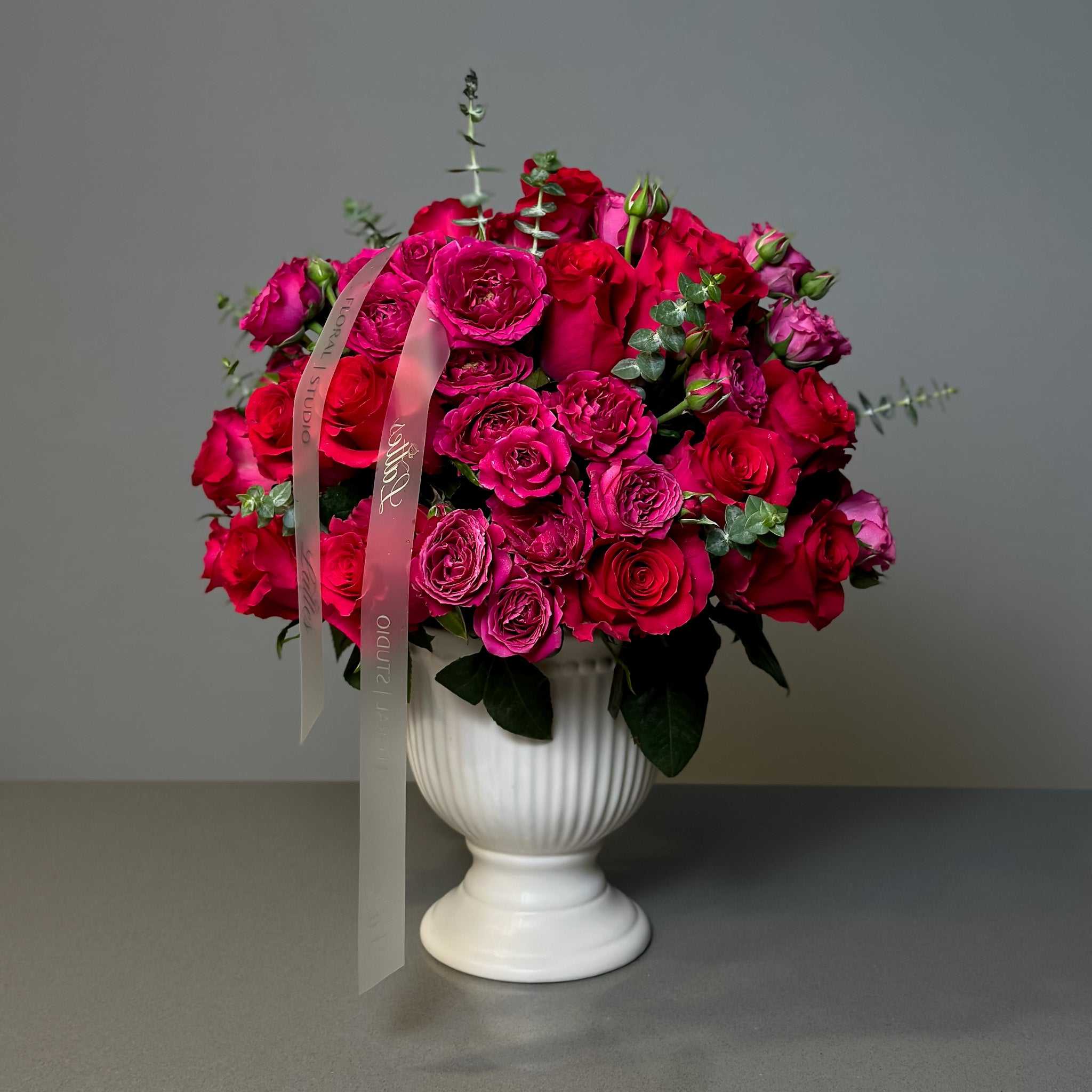 Fuchsia Bliss bouquet with vibrant magenta roses and eucalyptus in white ceramic vase
