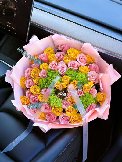 Lumiere de Provence bouquet with yellow and pink roses and green hydrangeas wrapped in pastel paper