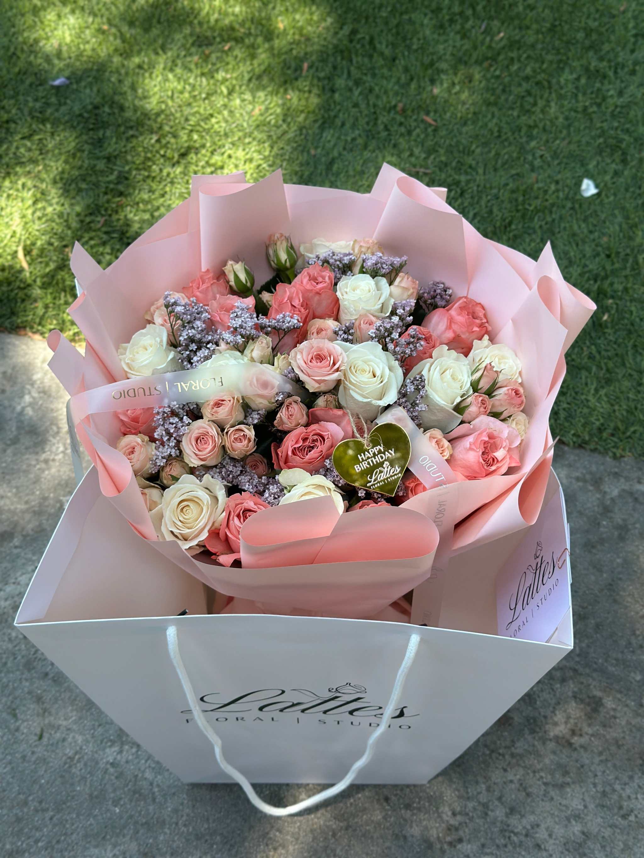 Romantic bouquet with pink roses, white roses, and spray roses in blush pink wrapping