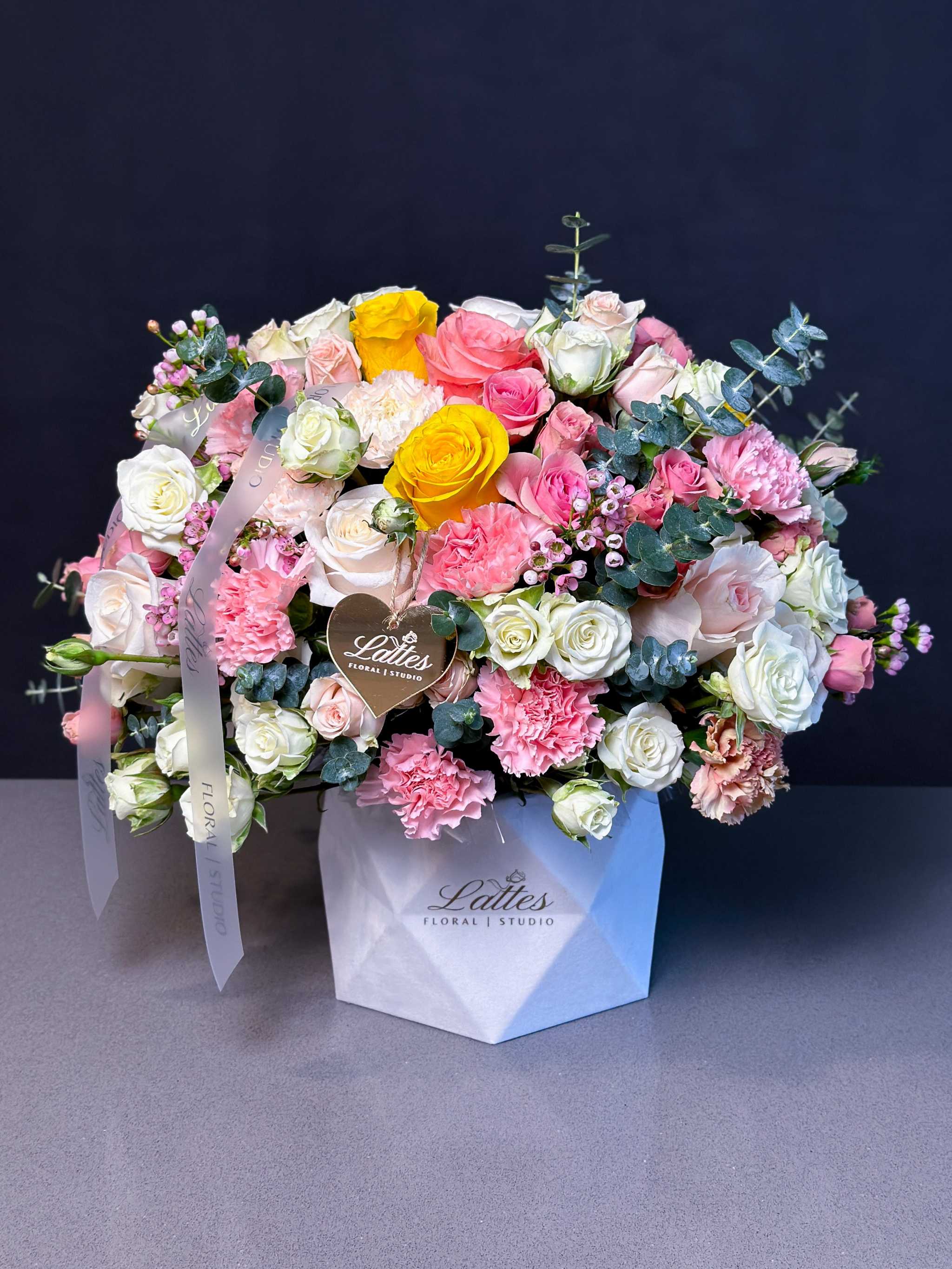 Aysémiq Flower Box with pink, white, and yellow roses, spray roses, carnations, wax flowers, eucalyptus in white geometric box