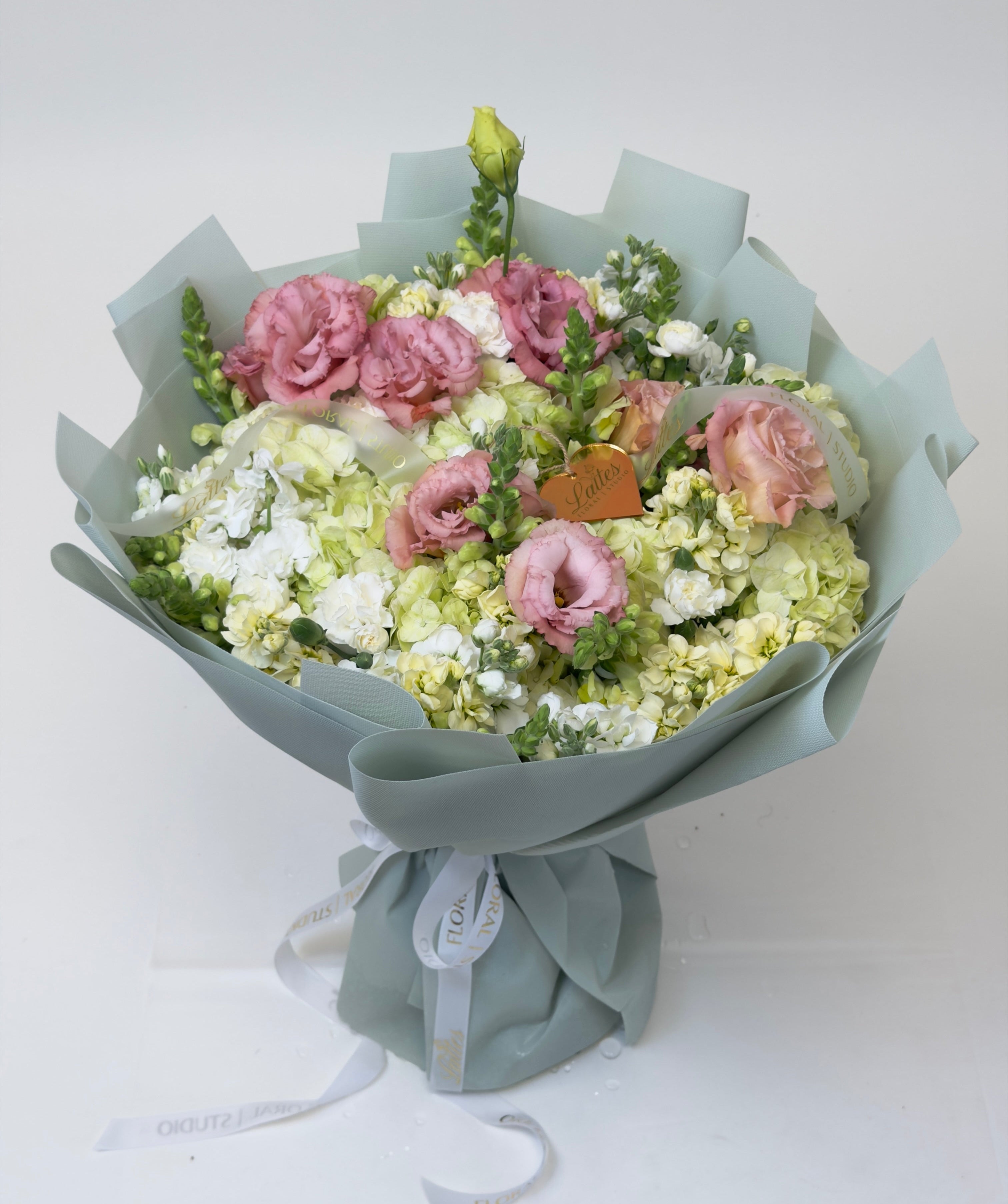 Sage Whisper dusty pink lisianthus green hydrangea bouquet wrapped in sage paper with gold heart charm for Irvine flower delivery