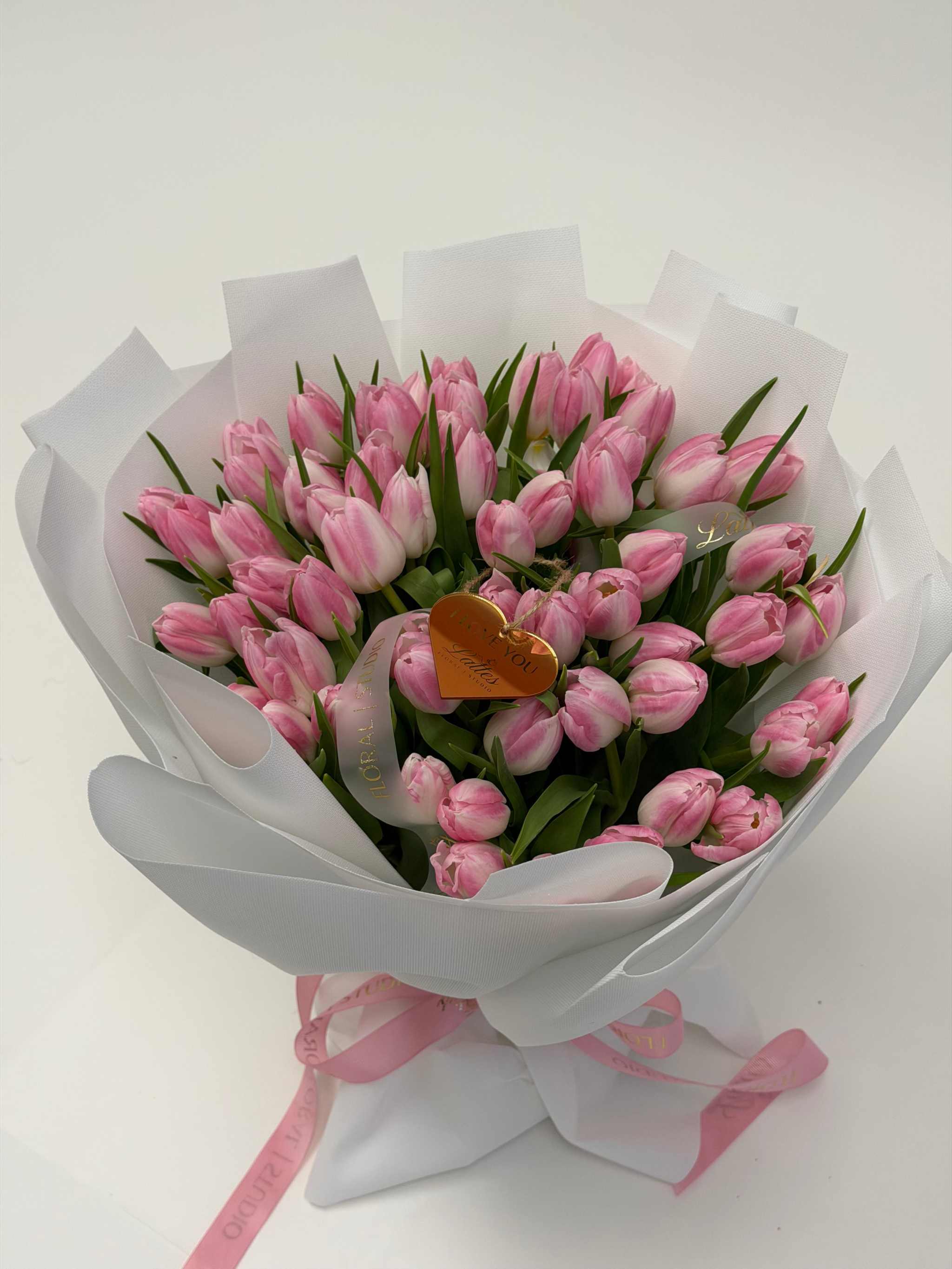 Light pink and white tulip bouquet with gold heart charm, wrapped in white paper, perfect for Newport Beach flower delivery