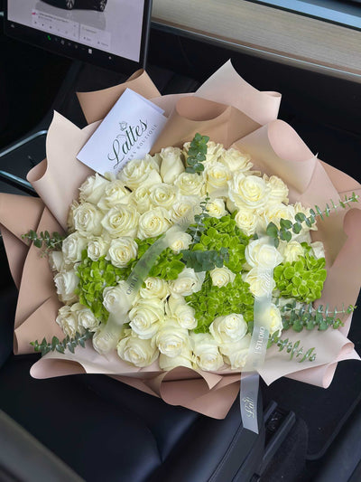 Jardin des Gérardmer bouquet with white roses, green hydrangeas, and eucalyptus in neutral wrapping