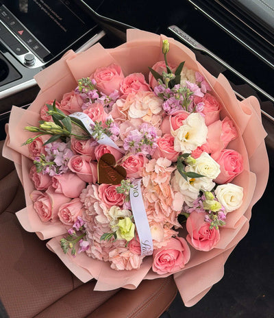 Pink roses, hydrangeas, lisianthus bouquet wrapped in dusty-rose paper for Tustin flower delivery