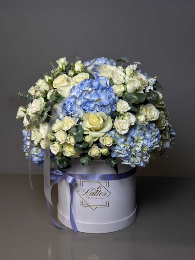 Heavenly Blues floral arrangement with blue hydrangeas, white roses, and eucalyptus in a white box with lavender ribbon