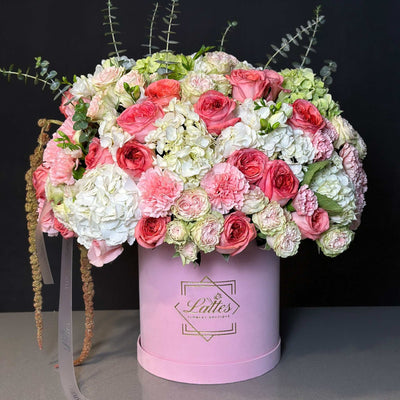 Blush Romance floral arrangement with pink and white roses, hydrangeas, spray roses, and eucalyptus in a soft pink luxury box.