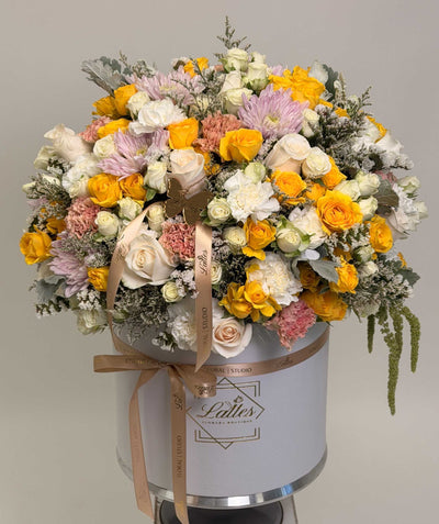 Amore floral arrangement with yellow and blush roses, pink chrysanthemums, and carnations in an elegant hatbox