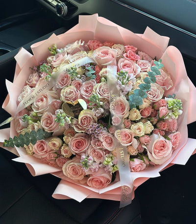 Blush Symphony flower bouquet with pink roses, spray roses, stock flowers, and eucalyptus greenery